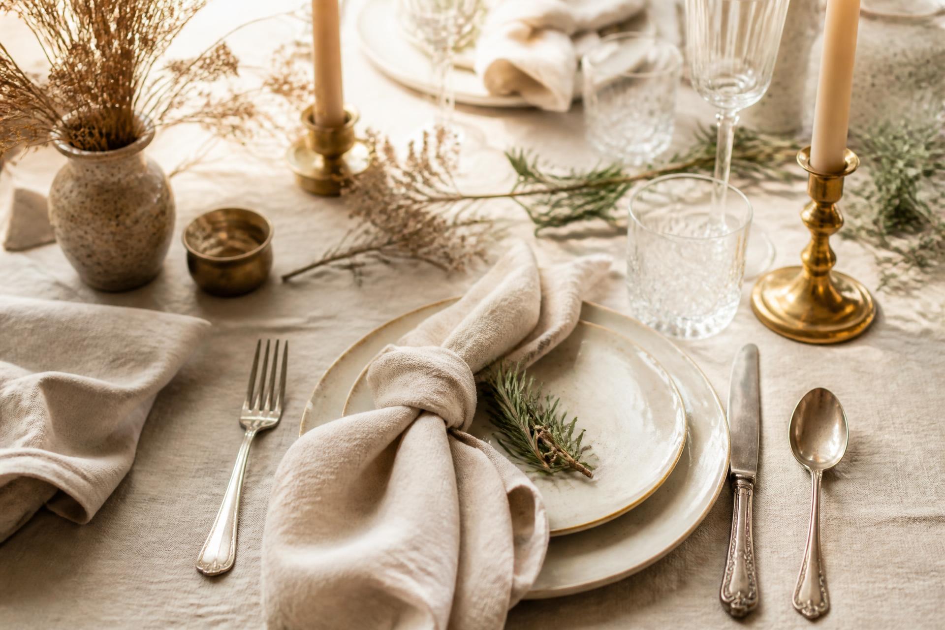 Warm editorial table setting with linen, candlelight, and rosemary
